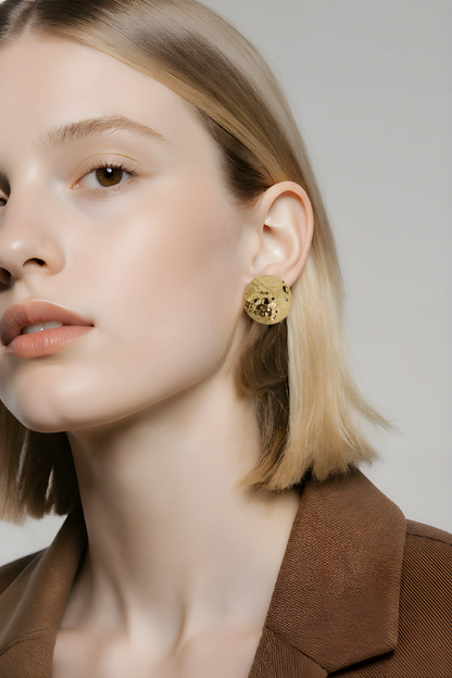 Kvinde med kort blondt hår bærer stor, rund, gylden ørering, elegant accessory