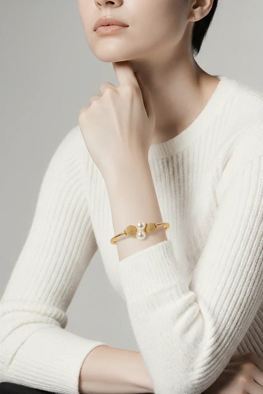 Elegant kvinde bærer gylden armbånd med perler, stilfuldt accessorie til mode og smykker