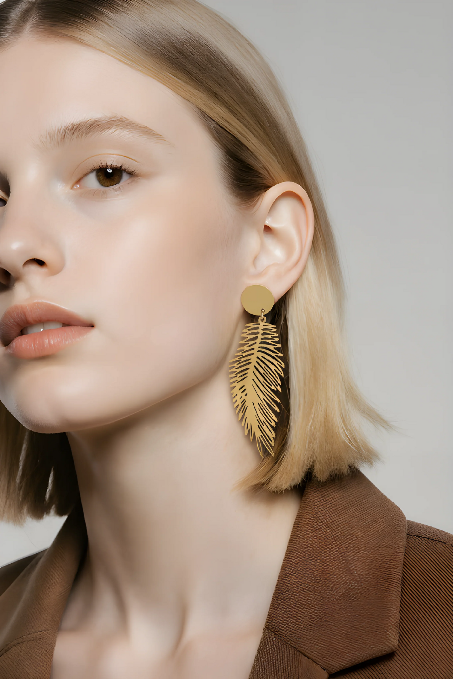 Kvinde med stort, gyldent fjer-ørering, moderne accessories, stilfuldt smykke
