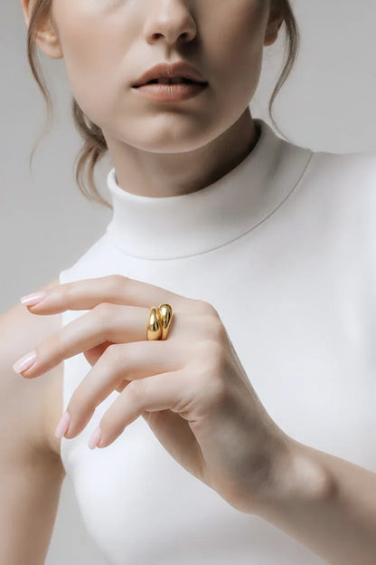 Elegant kvinde med stor gylden ring, smykkeaccessory, moderne stil, hvid baggrund
