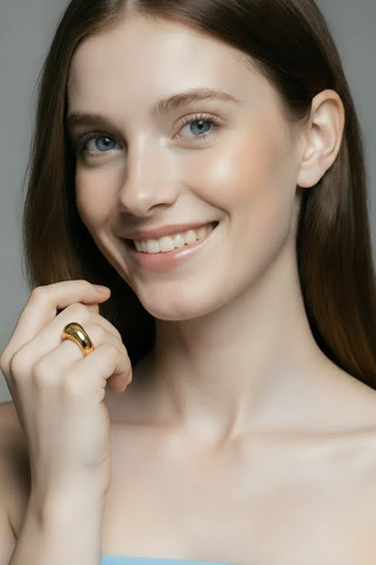 Kvinde med langt hår bærer elegant guldring, stilfuldt smykke og moderne accessories