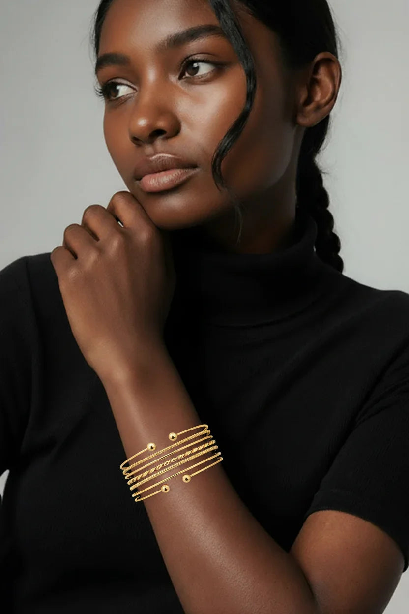 Kvinde med sort trøje bærer elegante guldbelagte armbånd, moderne smykke-accessory stil