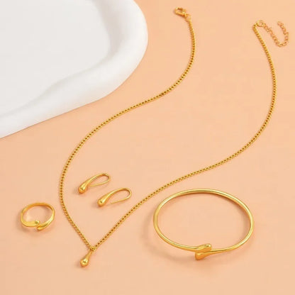 Elegant sæt med guldbelagt halskæde, ring, armbånd og øreringe på lys baggrund