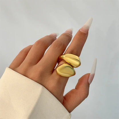 Trendy chunky guld ring med organisk form på hånd med hvide negle, stilfuldt smykke til kvinder