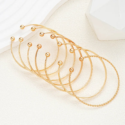 Sæt af elegante gyldne armbånd med kugledetaljer på neutral baggrund, smykker, accessories
