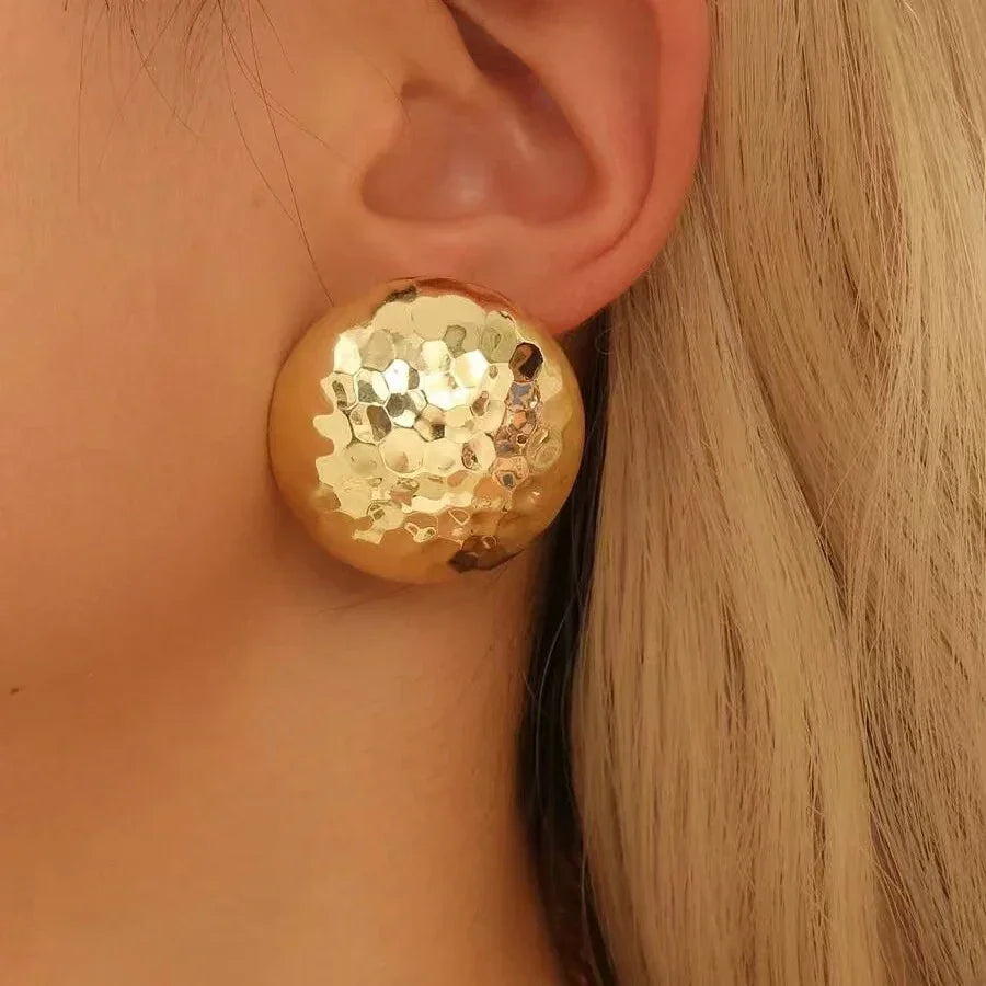 Stor ørestik i hamret guldlook på øre, moderne smykke og elegant accessory