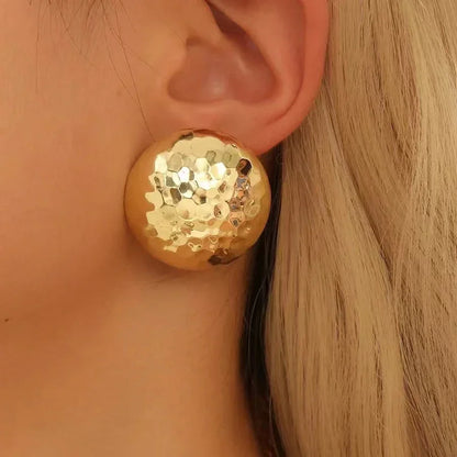 Stor ørestik i hamret guldlook på øre, moderne smykke og elegant accessory