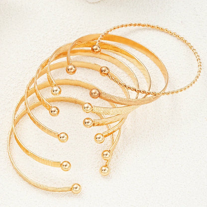 Elegant sæt af gyldne armbånd med kugleender, perfekt til moderne smykke-accessories