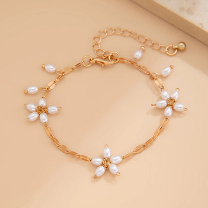Boho perle armbånd med guldfarvet kæde og blomsterdesign af hvide imitationsperler. Elegant smykke til boheme-stil fra Stylisk.