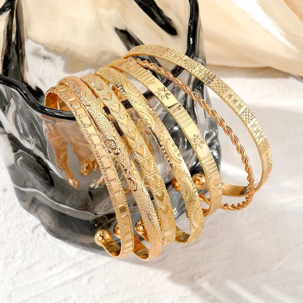 Sæt af gyldne armbånd i forskellige mønstre, elegante smykker på glasvase