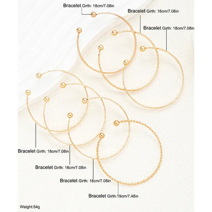 Seks elegante guldfarvede armbånd i forskellige designs og størrelser, perfekt som accessories.