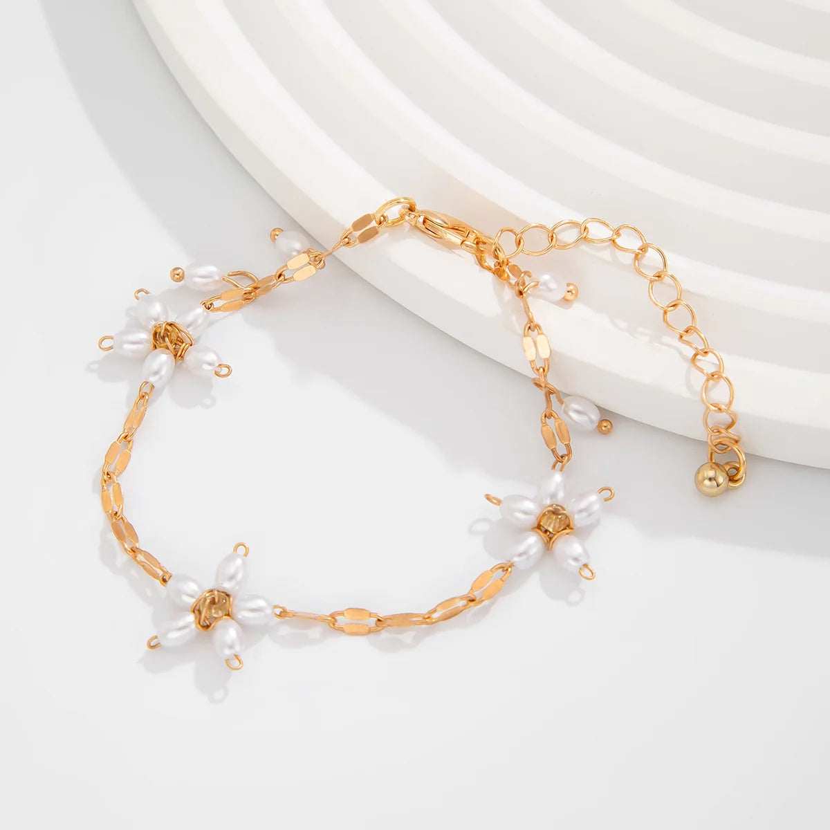 Boho perle armbånd med guldfarvet kæde og blomsterdesign i imiterede perler. Perfekt til boheme-look fra Stylisk smykkekollektion.