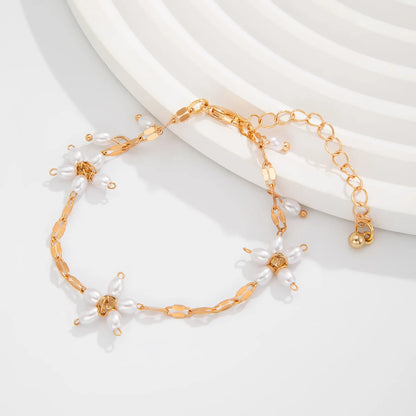 Boho perle armbånd med guldfarvet kæde og blomsterdesign i imiterede perler. Perfekt til boheme-look fra Stylisk smykkekollektion.