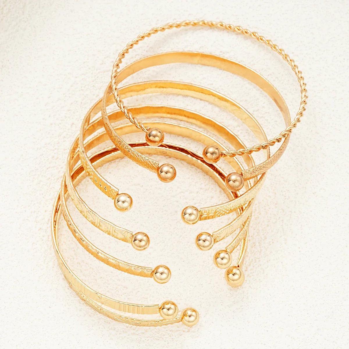 Sæt af stilfulde guldfarvede armbånd med kugleender, elegant smykkeaccessory