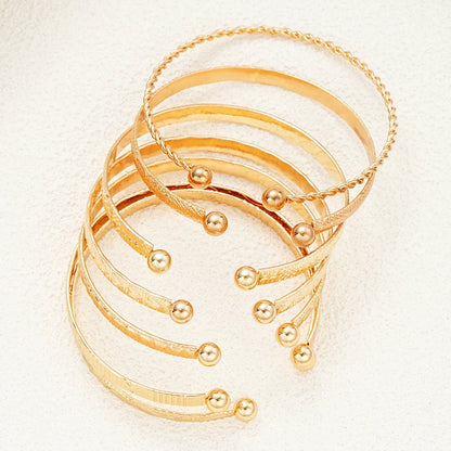 Sæt af stilfulde guldfarvede armbånd med kugleender, elegant smykkeaccessory
